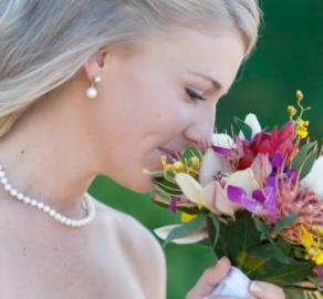 There's nothing more beautiful than a glowing bride on her wedding day. Here you see a photo of a bride enjoying the aroma of her unique wedding bouquet. 